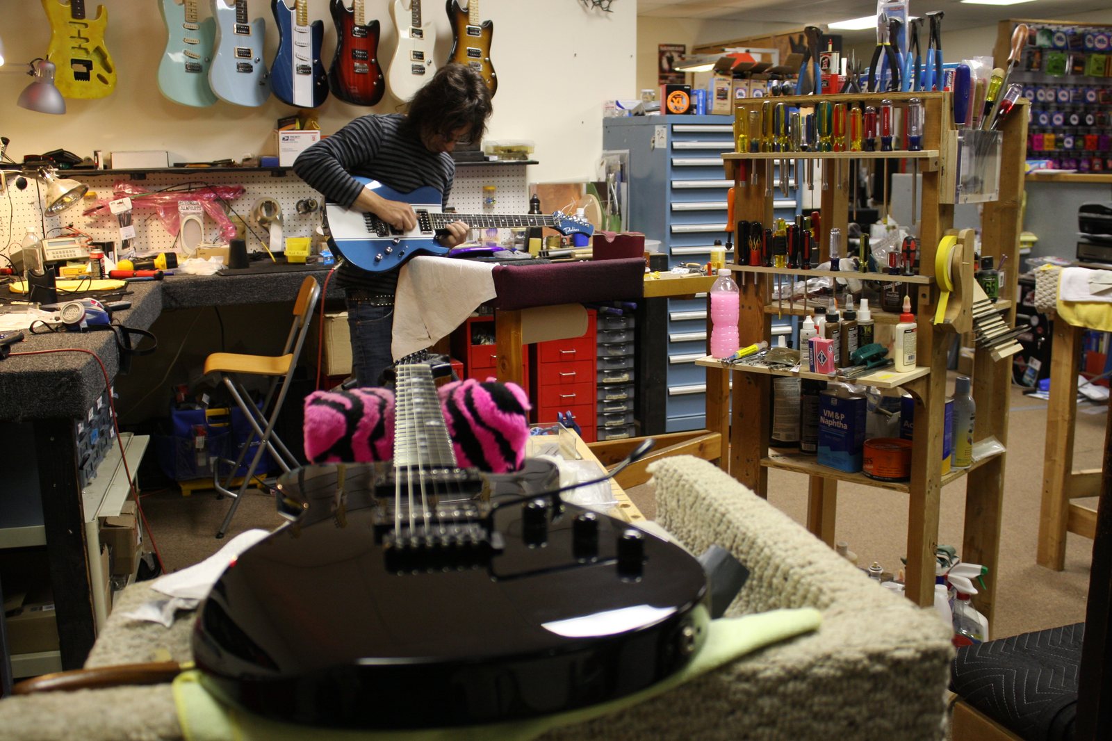 A luthier at the Hot Rod 6 Strings repair bench, surrounded by tools